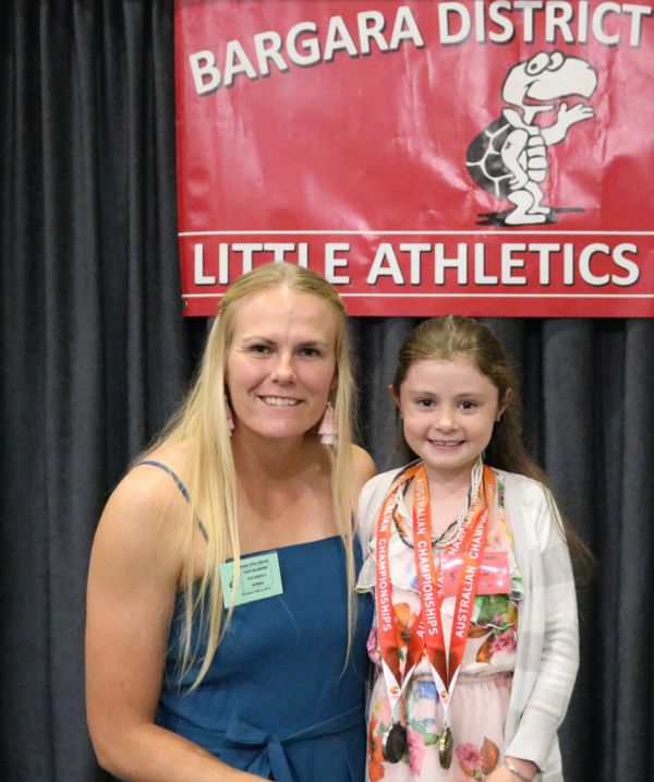 Taryn Gollshewsky shares her recent medals with young athlete Mia Edwards at the Bargara Little Aths 25th anniversary.