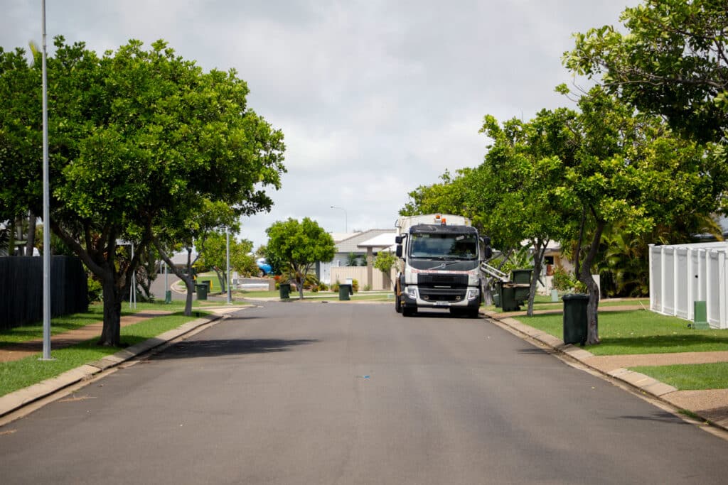Garbage truck collecting waste and recycling bins.