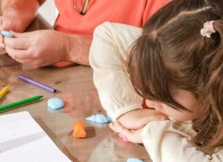 Young and old participants create seashell art together.