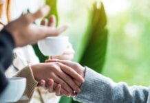 People shake hands over a cup of coffee.