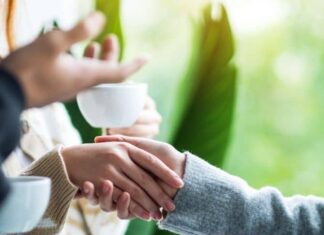 People shake hands over a cup of coffee.
