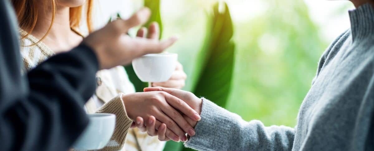 People shake hands over a cup of coffee.