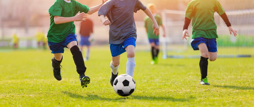 kids running on a field after a soccer ball