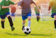 kids running on a field after a soccer ball