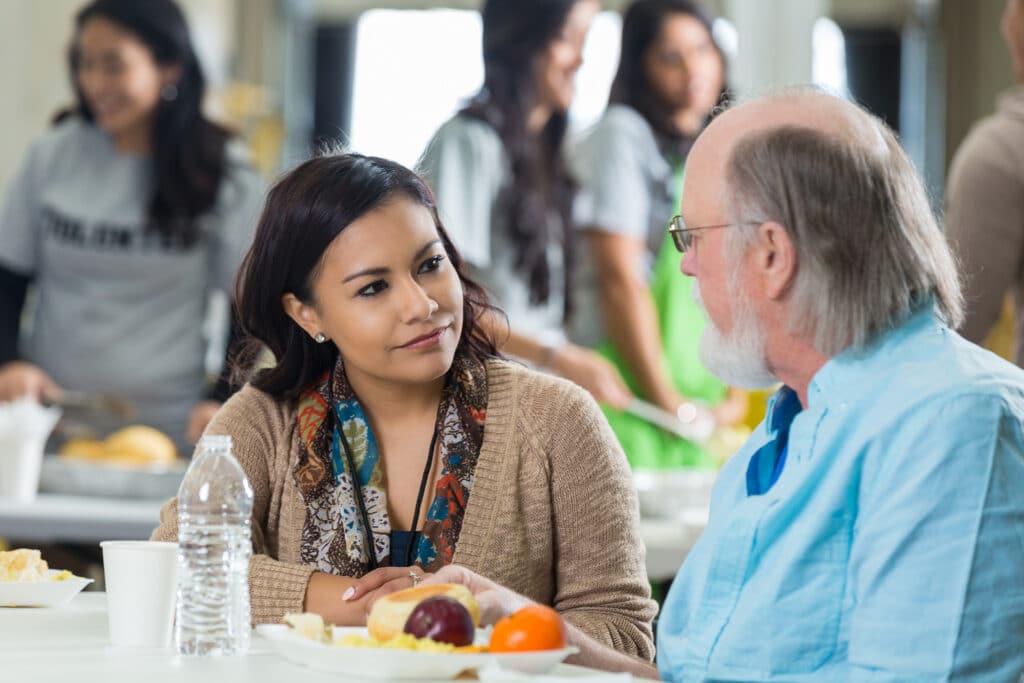 Volunteer having lunch with a senior man